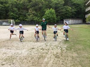 小学生と一緒に一輪車をする中学生