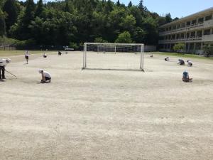 運動場をきれいにする高学年の子供たち