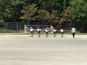 5人で手をつないで一輪車に乗るところ
