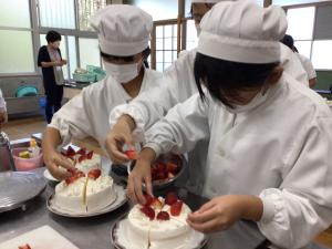 ケーキにイチゴを載せる子ども